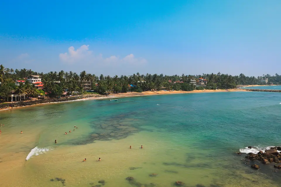 Mirissa’s curving beach and blue ocean seen from above
